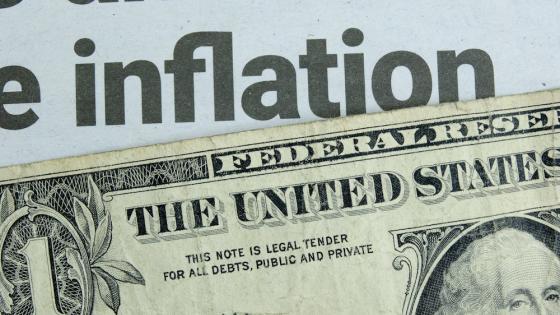A US one dollar bill lying below a newspaper headline news on inflation.